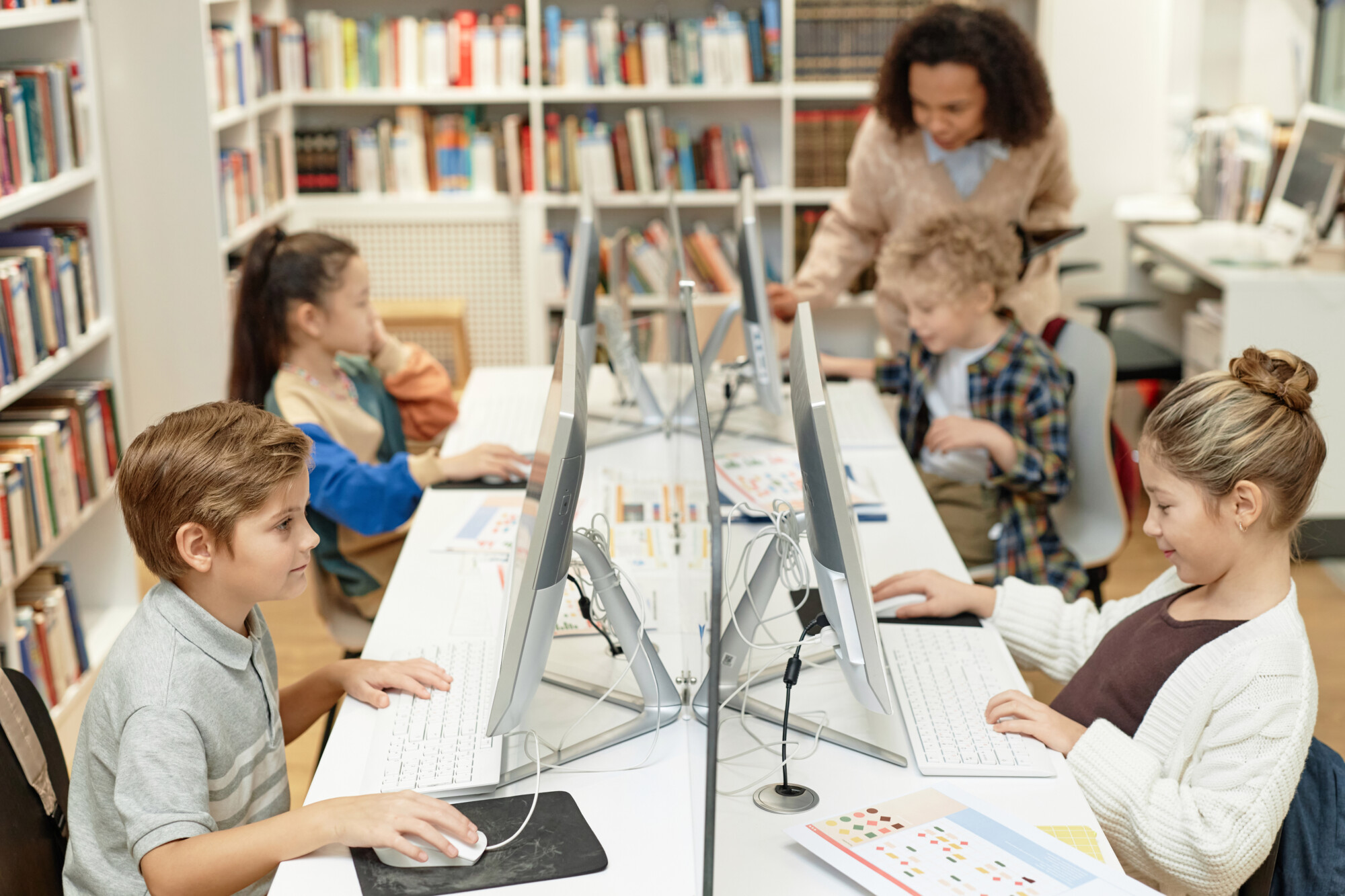 High angle view at group of young school children using computers during IT programming class for kids and smiling