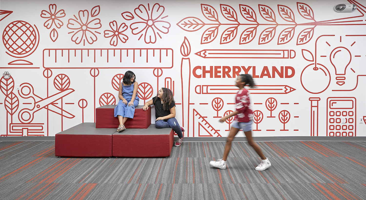 Image of students sitting in and walking through common open space in an interior of a modern school facility.