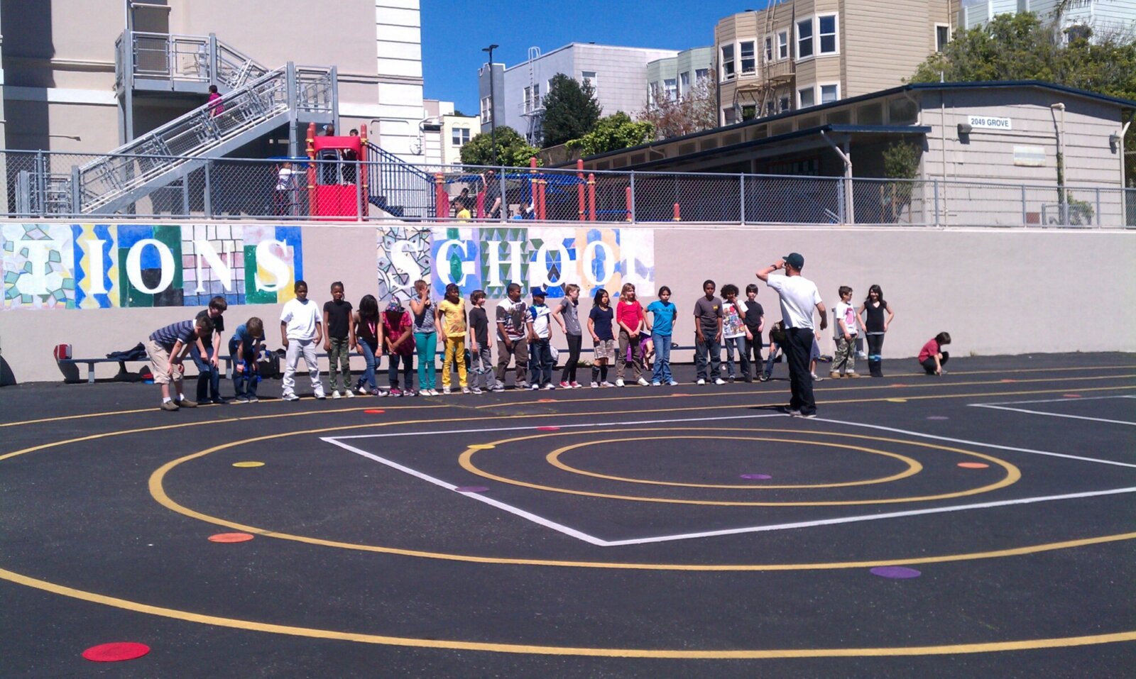 Image of a teacher and students using an outdoor gym space