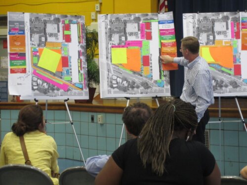 Image of adults interacting with posterboard maps at a workshop on school facilities master planning
